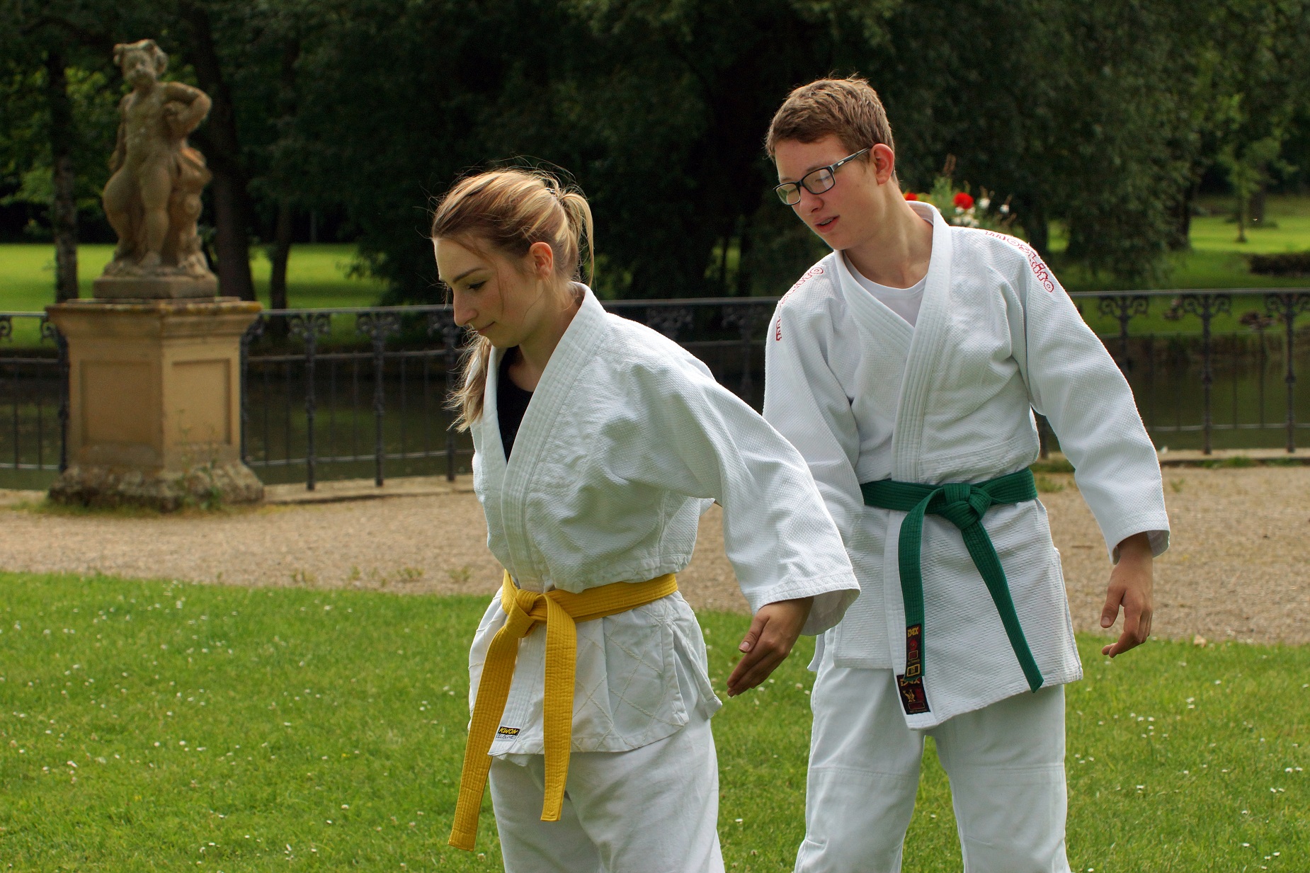 Bild: Zwei Judokas, im Judoanzug stehen im Schlosspark und machen eine Übung.