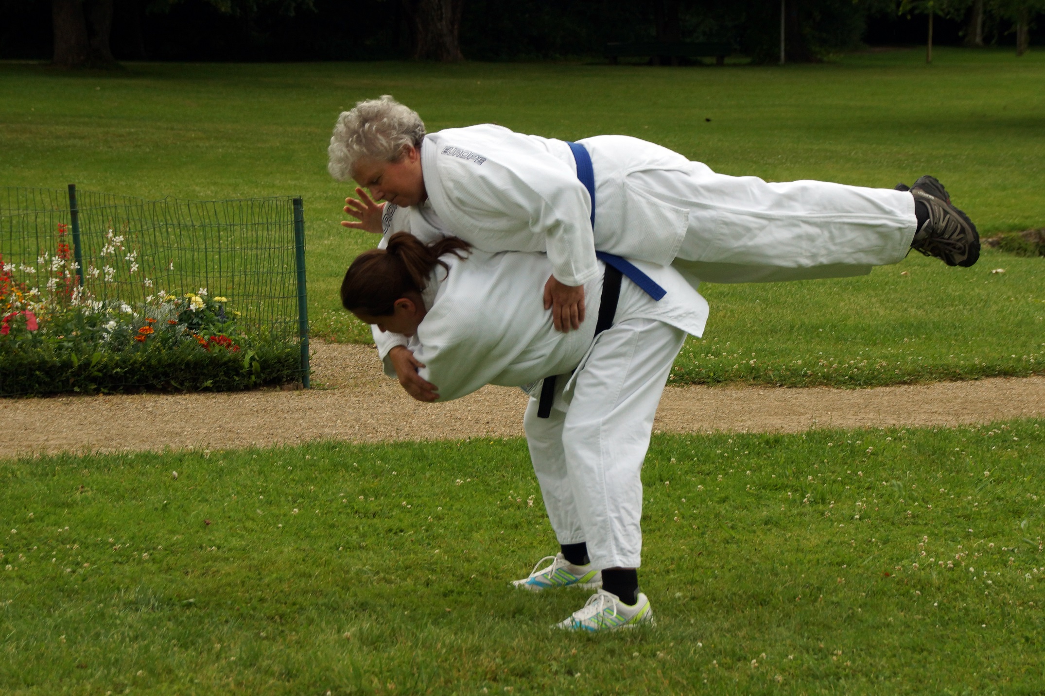 Bild: Ein Judoka liegt mit dem Bauch auf dem Rücken eines andren Judokas, das sich nach vorne beugt.