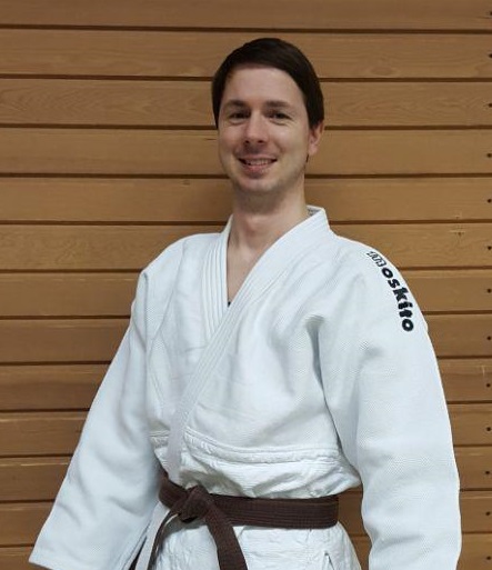 Porträ von Martin Adler, im Judo Anzug vor einer Holzwand.