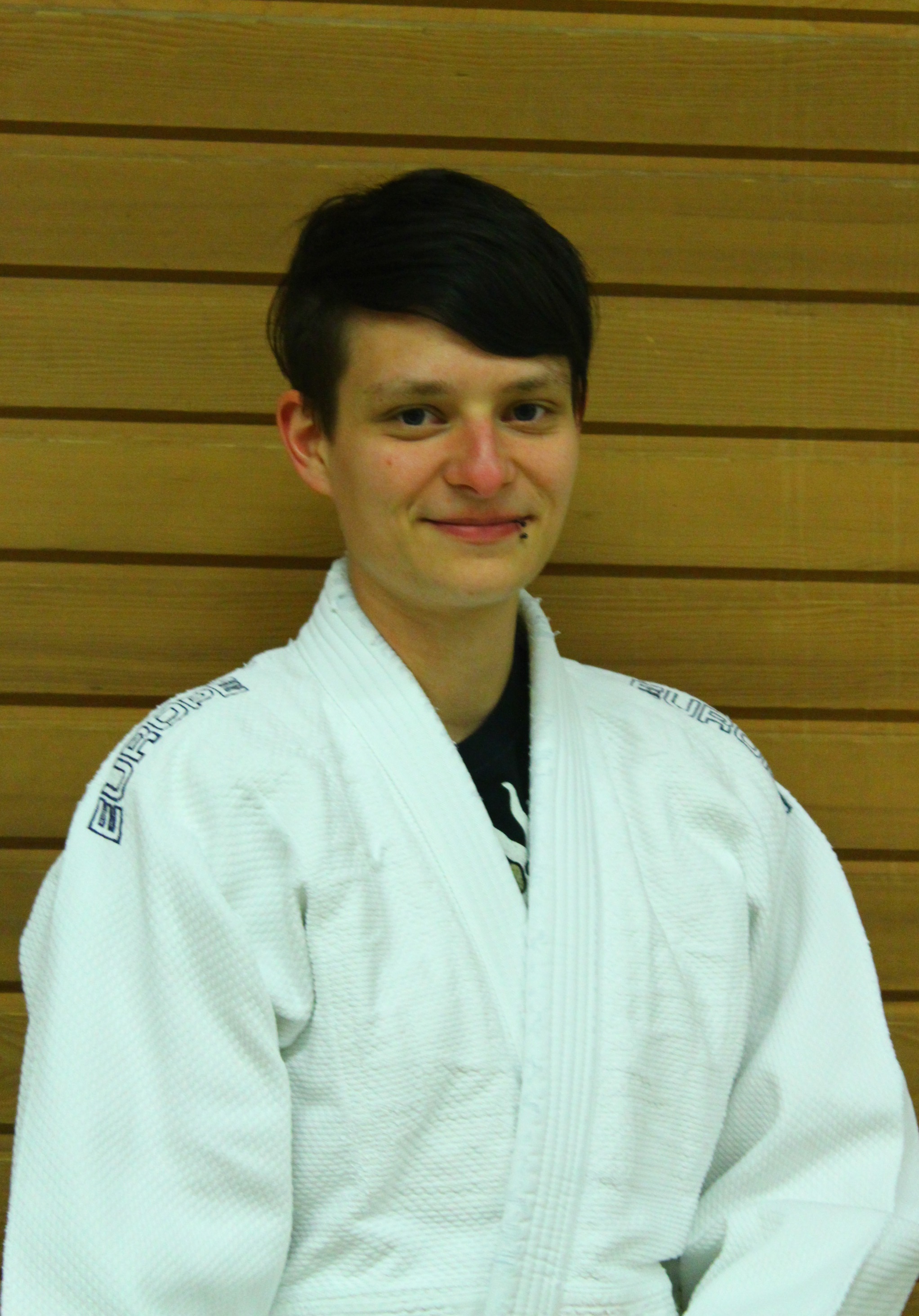 Porträ von Sabrina Kestler, im Judo Anzug vor einer Holzwand.